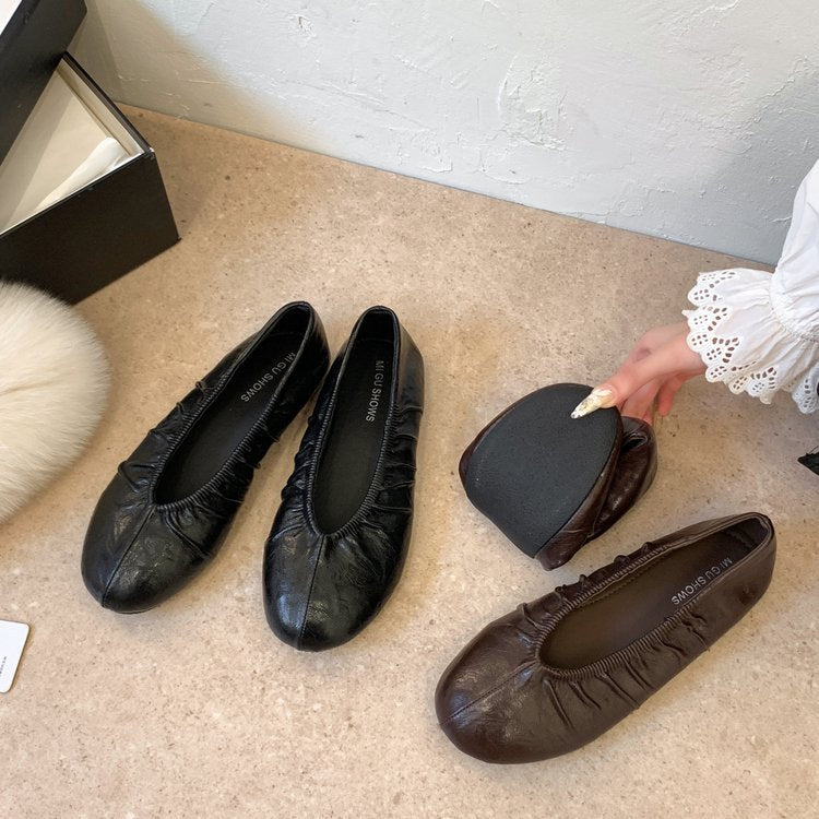 Black and brown pleated ballet flats on a light floor