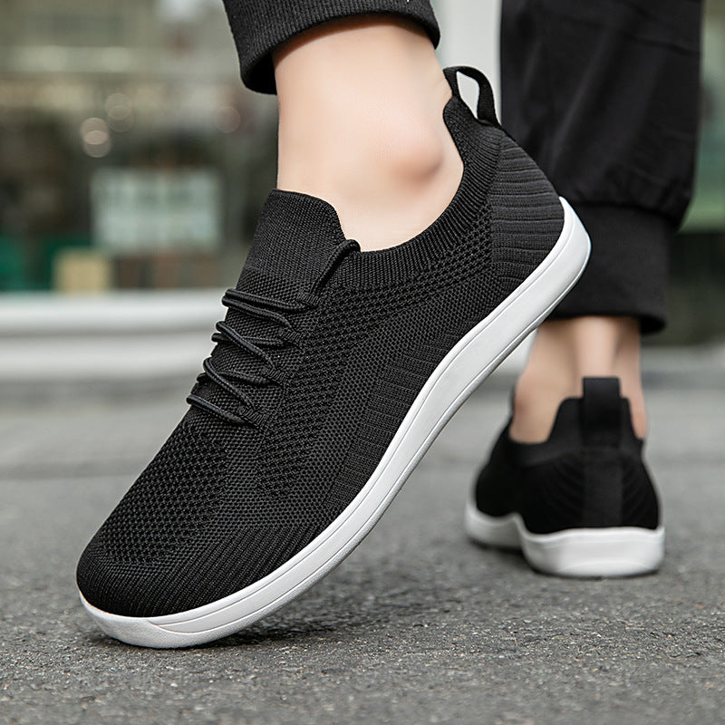 Black knit sneakers with white soles worn on pavement