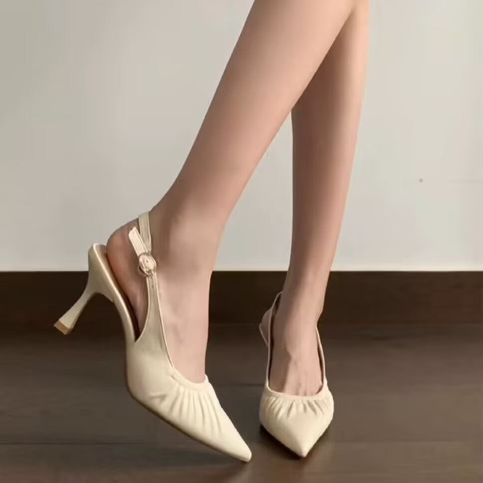 Beige ruched pointed slingbacks with flared slim heels, worn on foot