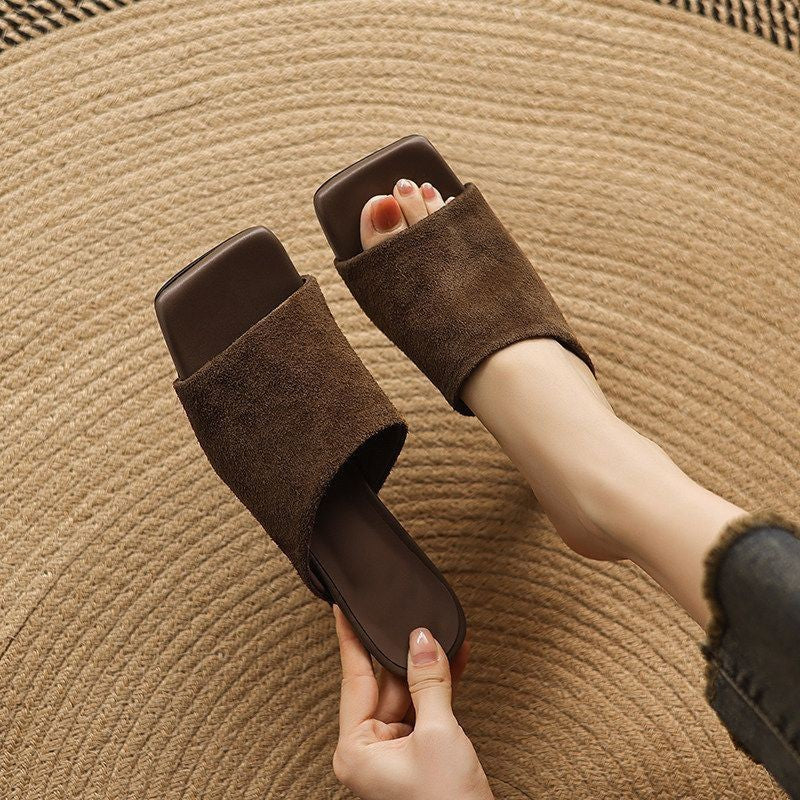 Woman holding a brown suede square-toe mule