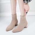 Woman pulling on khaki sock ankle boots with low block heels