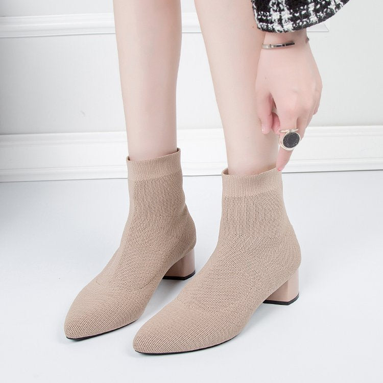 Woman pulling on khaki sock ankle boots with low block heels