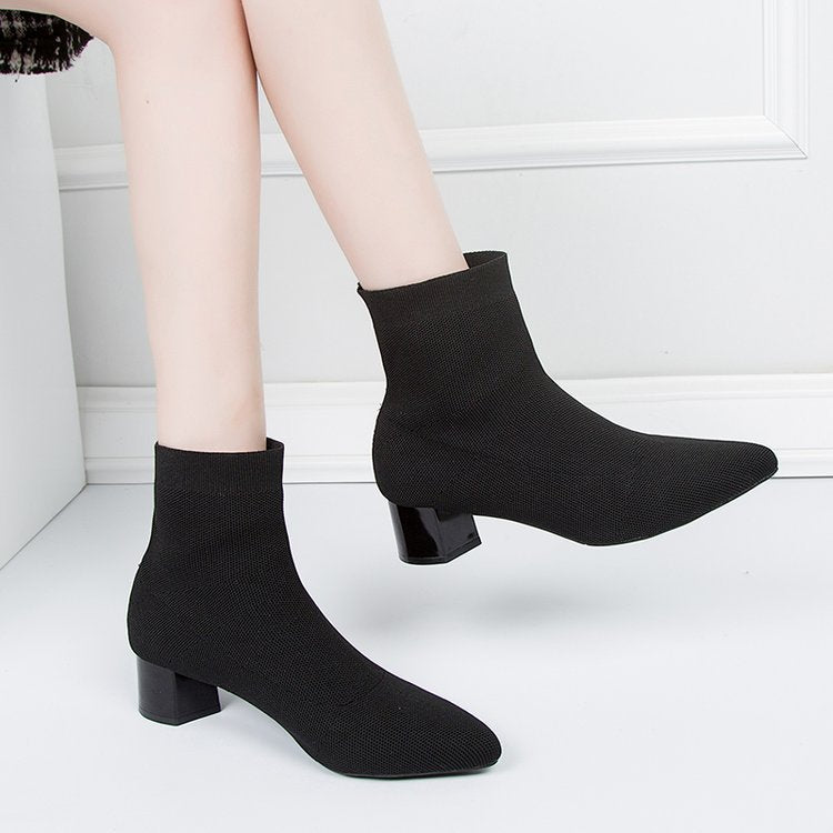 Woman wearing black pointed-toe sock ankle boots, side view