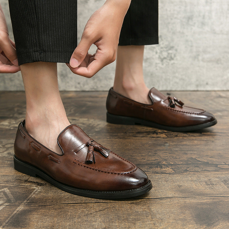 Man wearing brown tassel loafers, adjusting his trouser hem