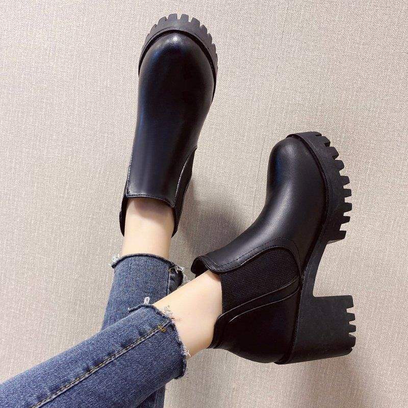 Woman wearing black lug-sole Chelsea ankle boots with jeans, top view