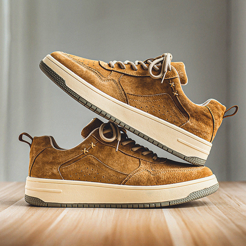 Pair of tan brushed low-top court sneakers stacked on a wood floor