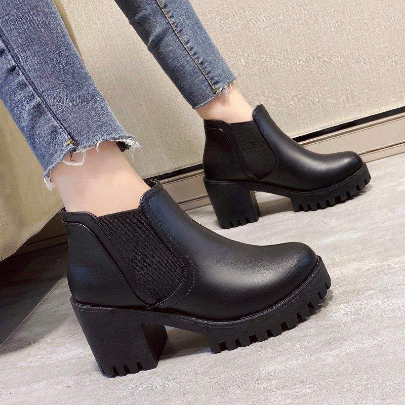 Side view of black Chelsea ankle boots with block heels worn with cropped jeans