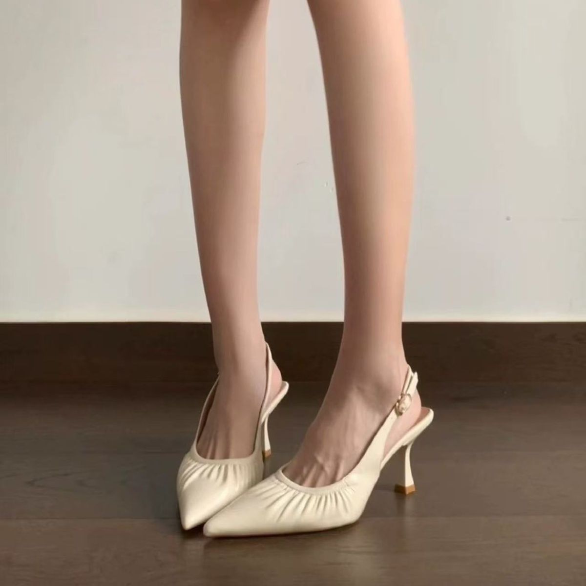 Front view of beige ruched pointed slingbacks worn on foot