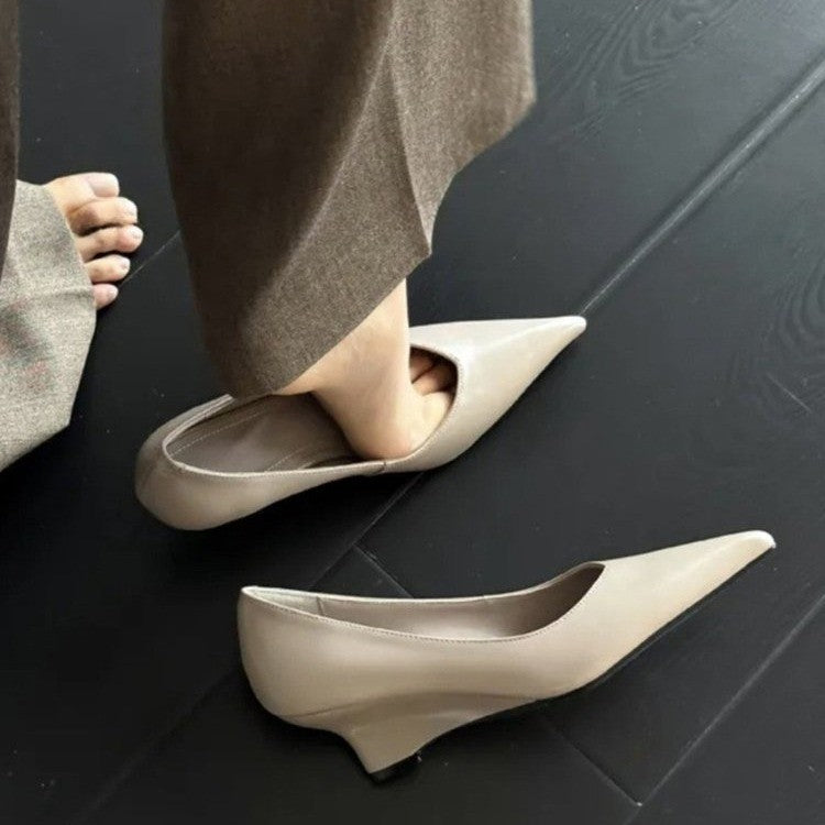 Taupe pointed low-heel pumps, one worn and one on the floor