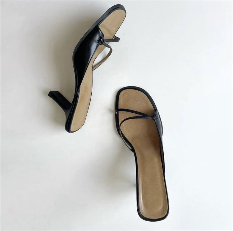 Black strappy heeled sandals, one turned on its side