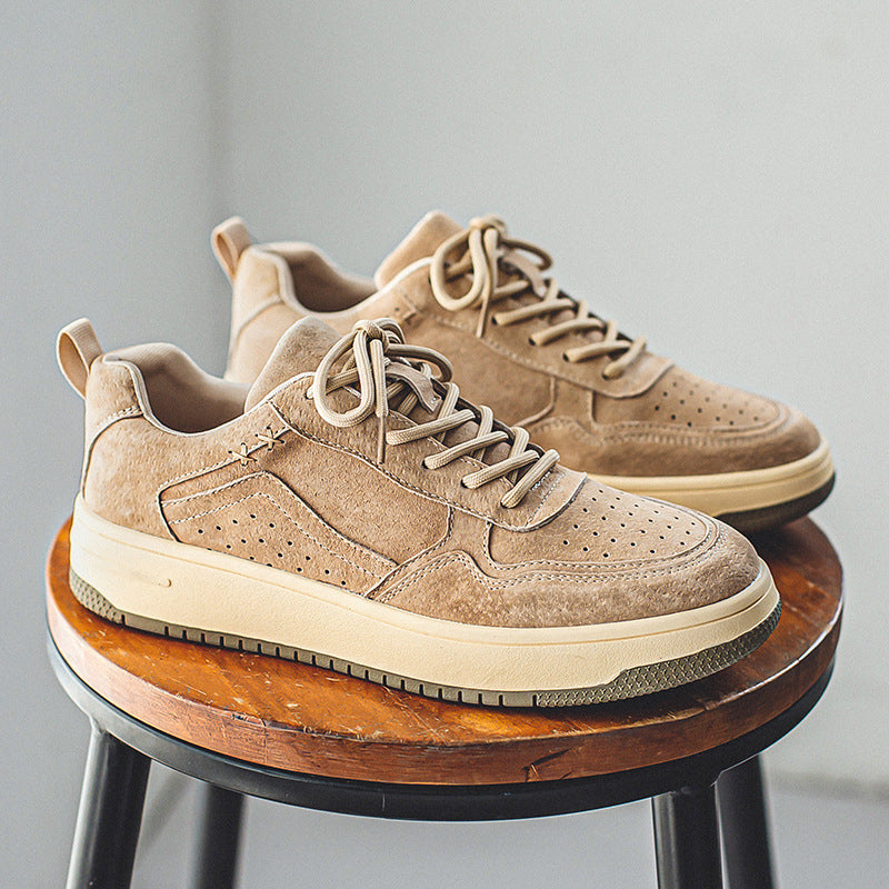 Pair of men's beige brushed low-top court sneakers on a wooden stool