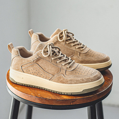 Pair of men's beige brushed low-top court sneakers on a wooden stool