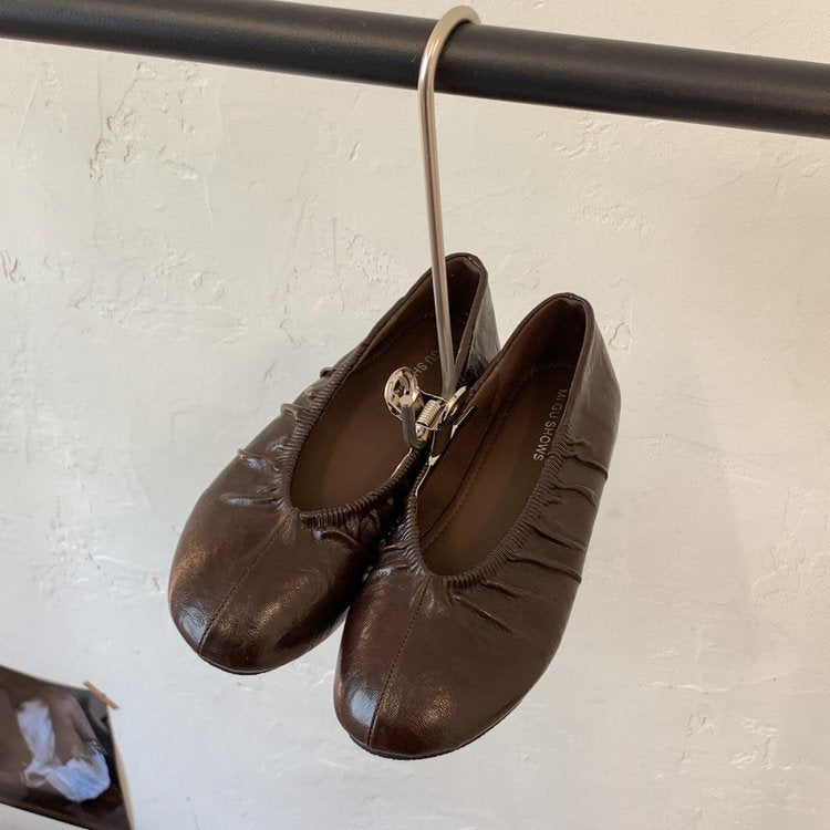 Brown pleated ballet flats hanging from a rail