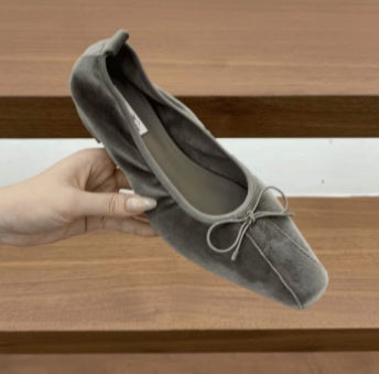 Gray square-toe ballet flat with a bow detail held in hand